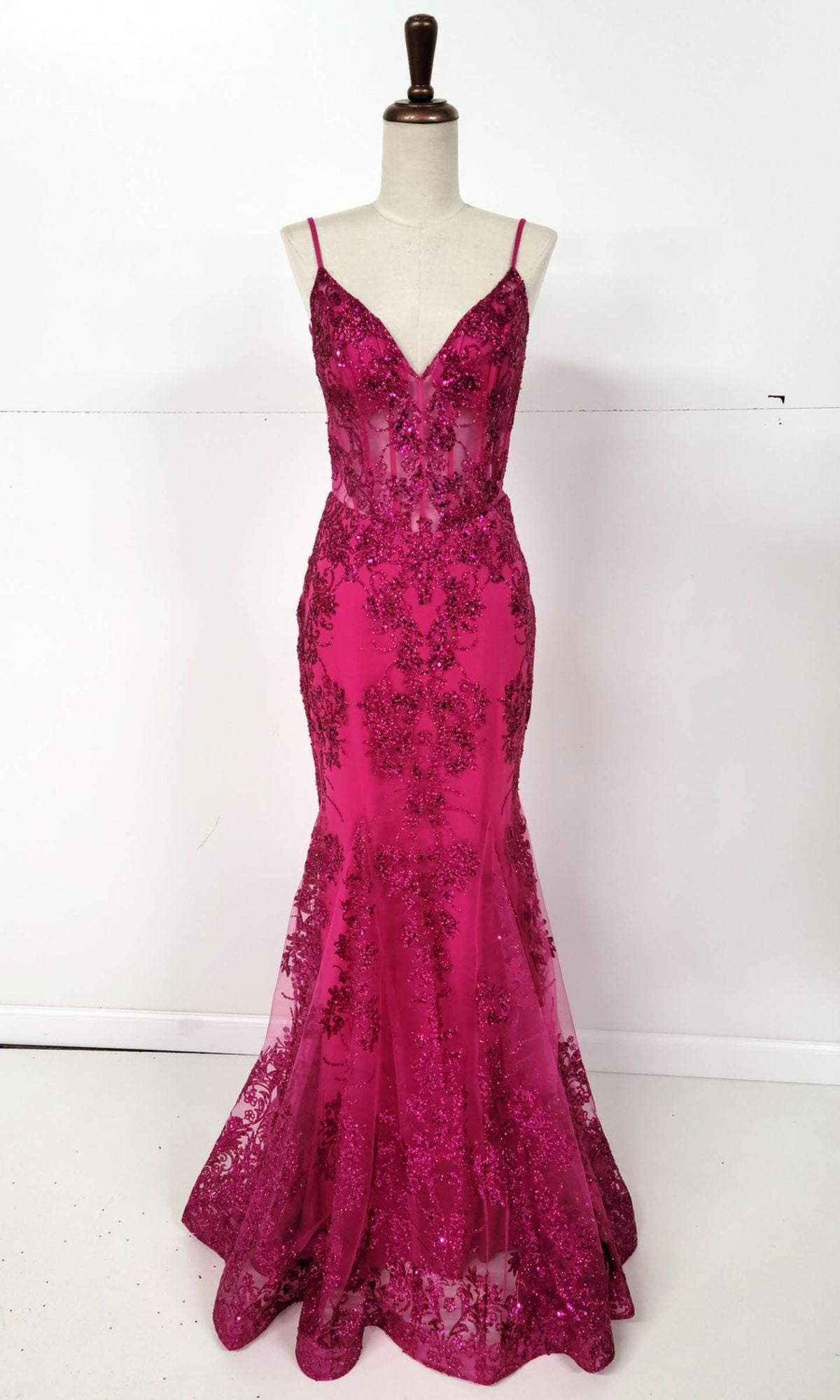 A mannequin displays the Long Glitter-Print Prom Dress: Chicas C813—a sleeveless deep pink mermaid gown with thin straps, a sheer corset waist, and glittery lace and sequin detailing.
